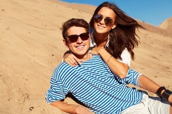 romantic-couple-with-sunglasses-lying-sand_1140-420